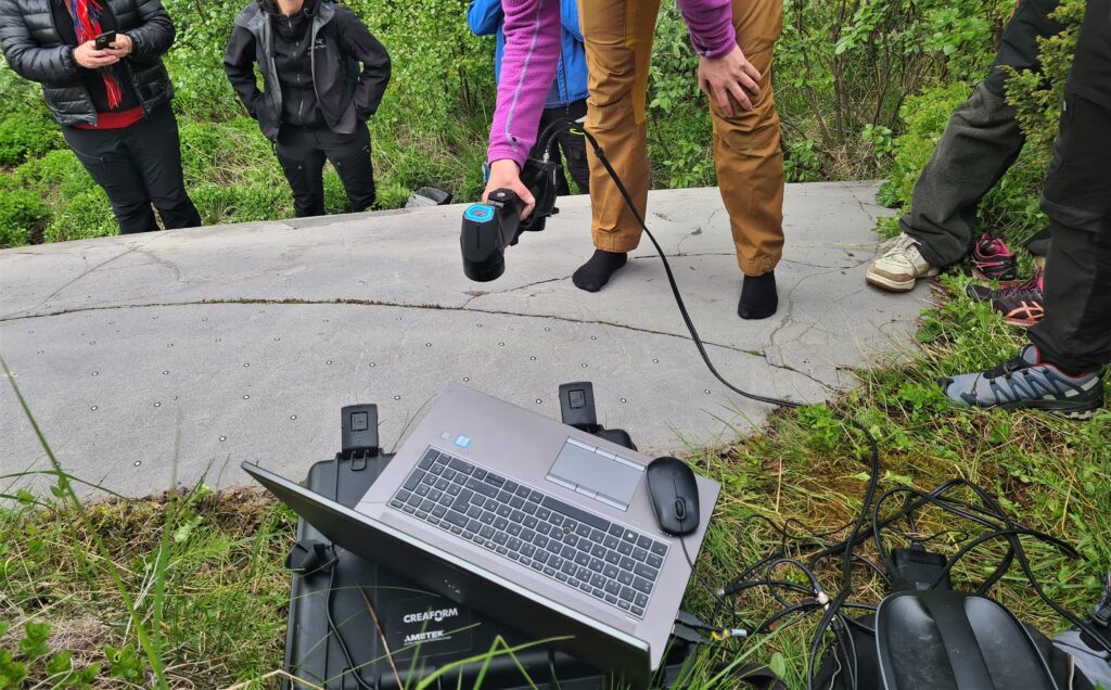 Fotot visar en person som skannar hällristningar, framför hällen står en dator.