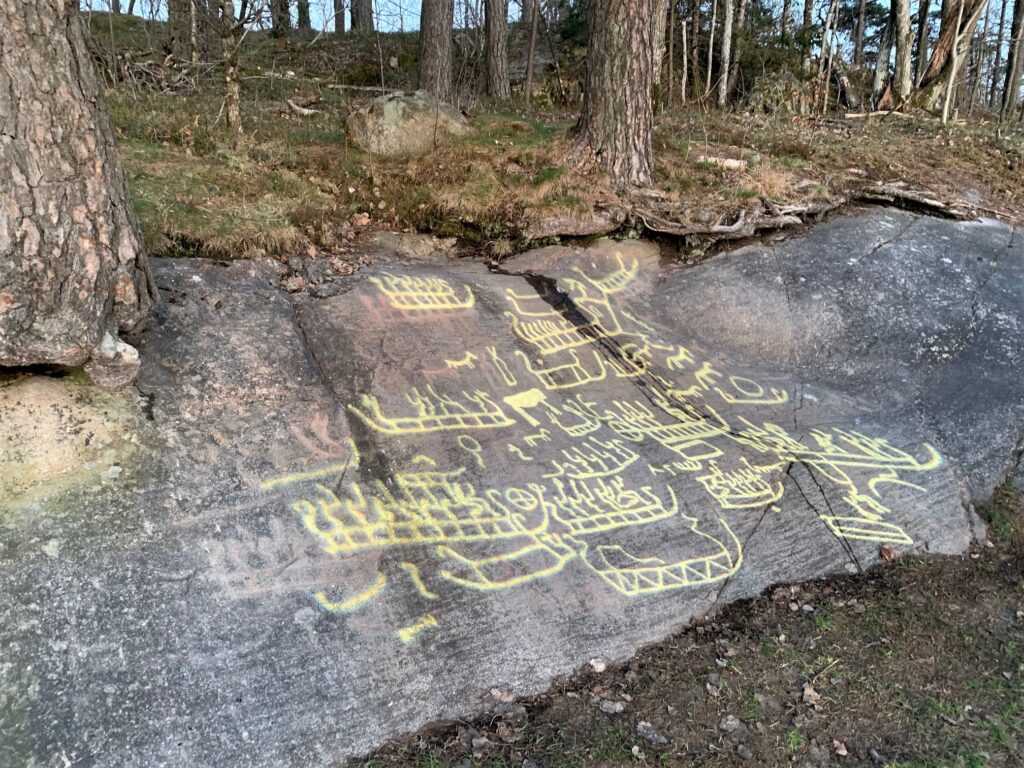 Fotot visar en häll, på hällen projiceras ljusristningar ovanpå de riktiga ristningarna.